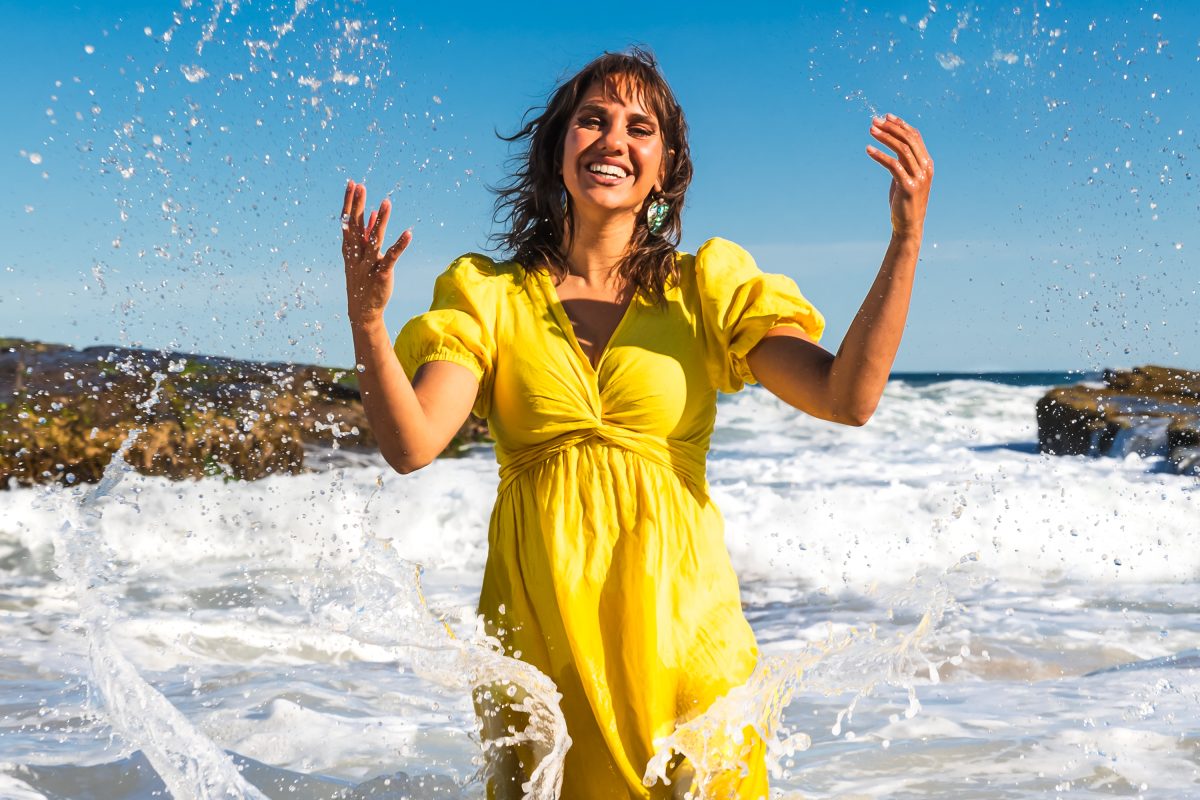 Kirli Saunders in a vivid yellow dress splashes beach water