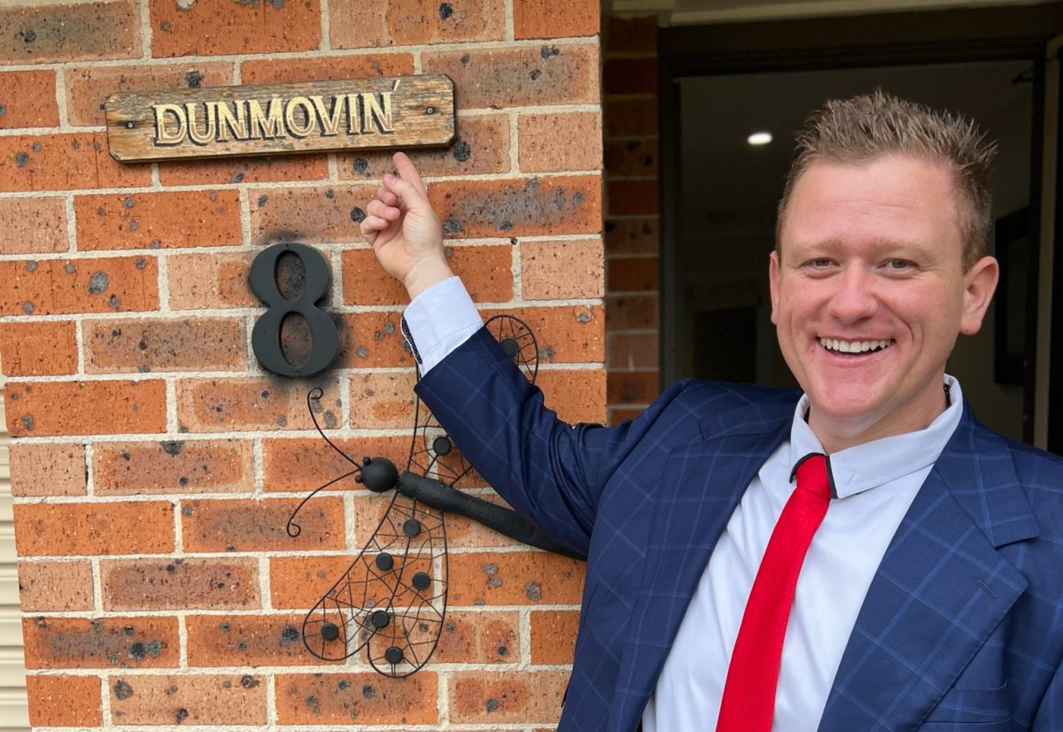 Man pointing to house name sign