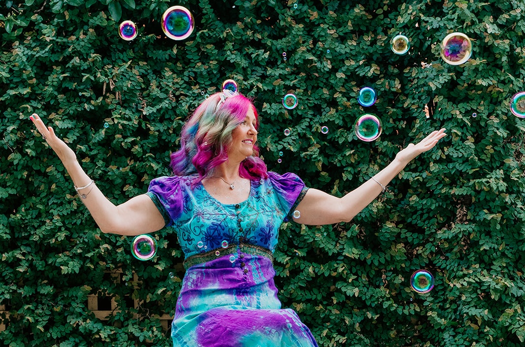 Rainbow Shiva in a colourful tie dye dress catching bubbles