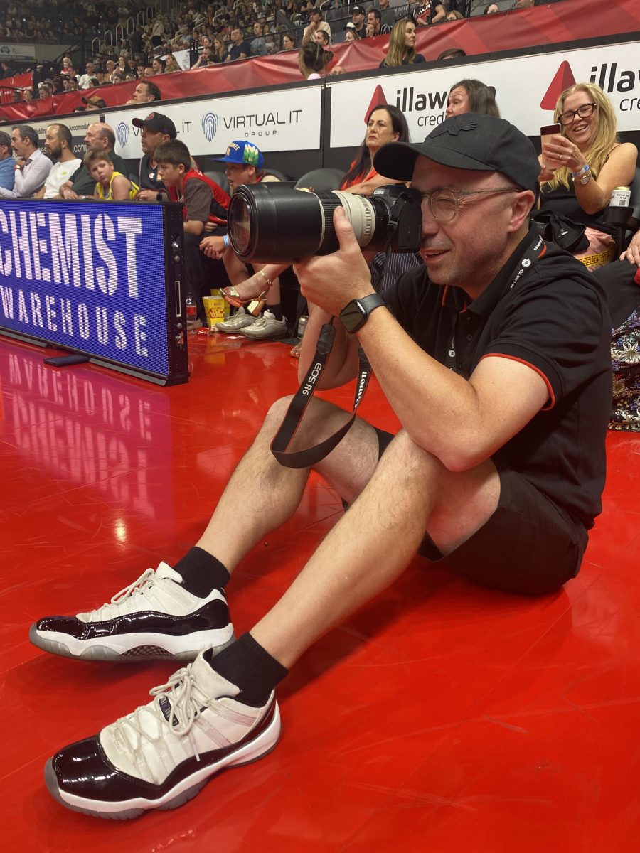 Joel in his favourite place, behind his camera at a Hawks game.