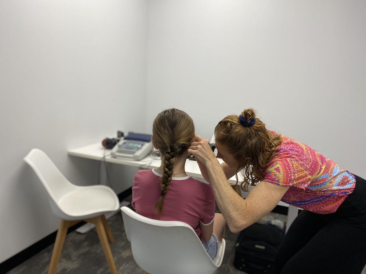 woman checking a young girl's hearing