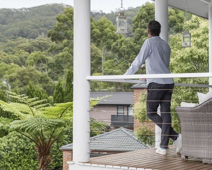 Man stands on balcony looking at Illawarra escarpment