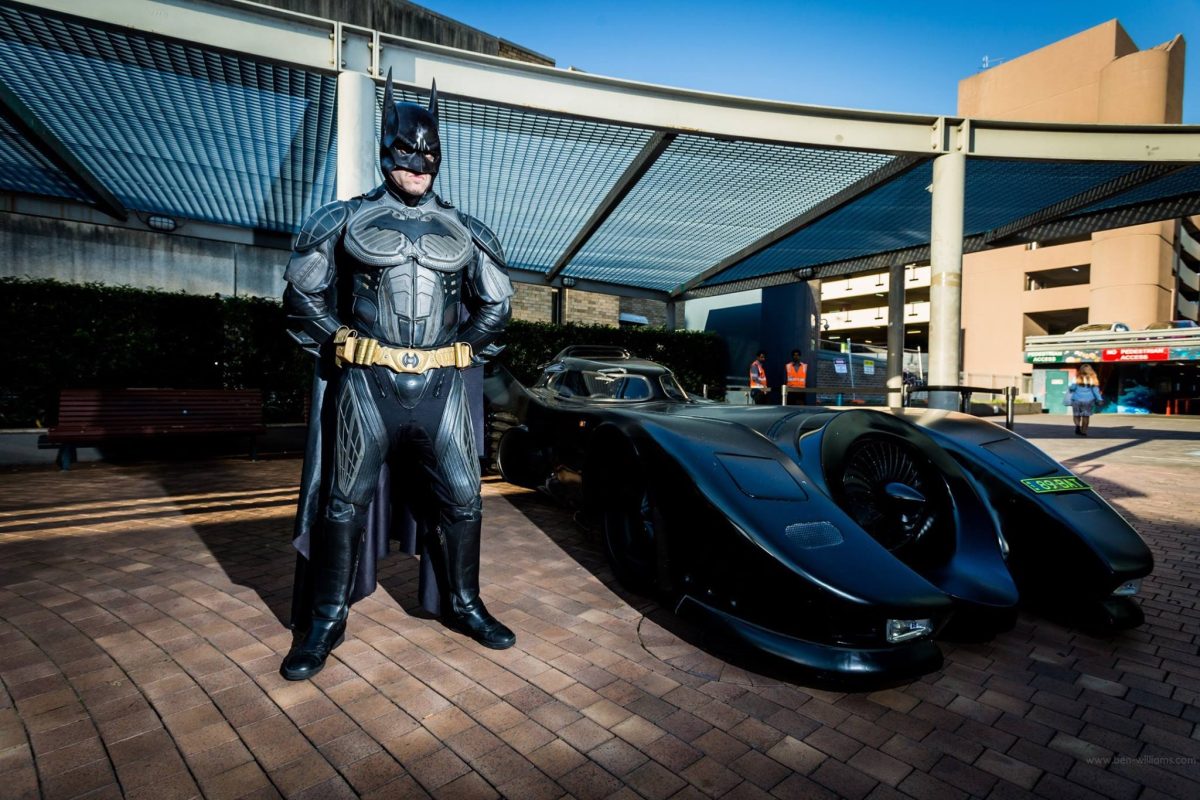 Zac Mihajlovic dressed as Batman next to his fully road certified Batmobile