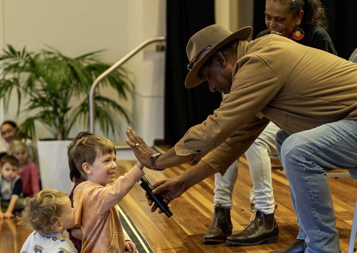 Child hi-fives an Aboriginal elder on National Sorry Day