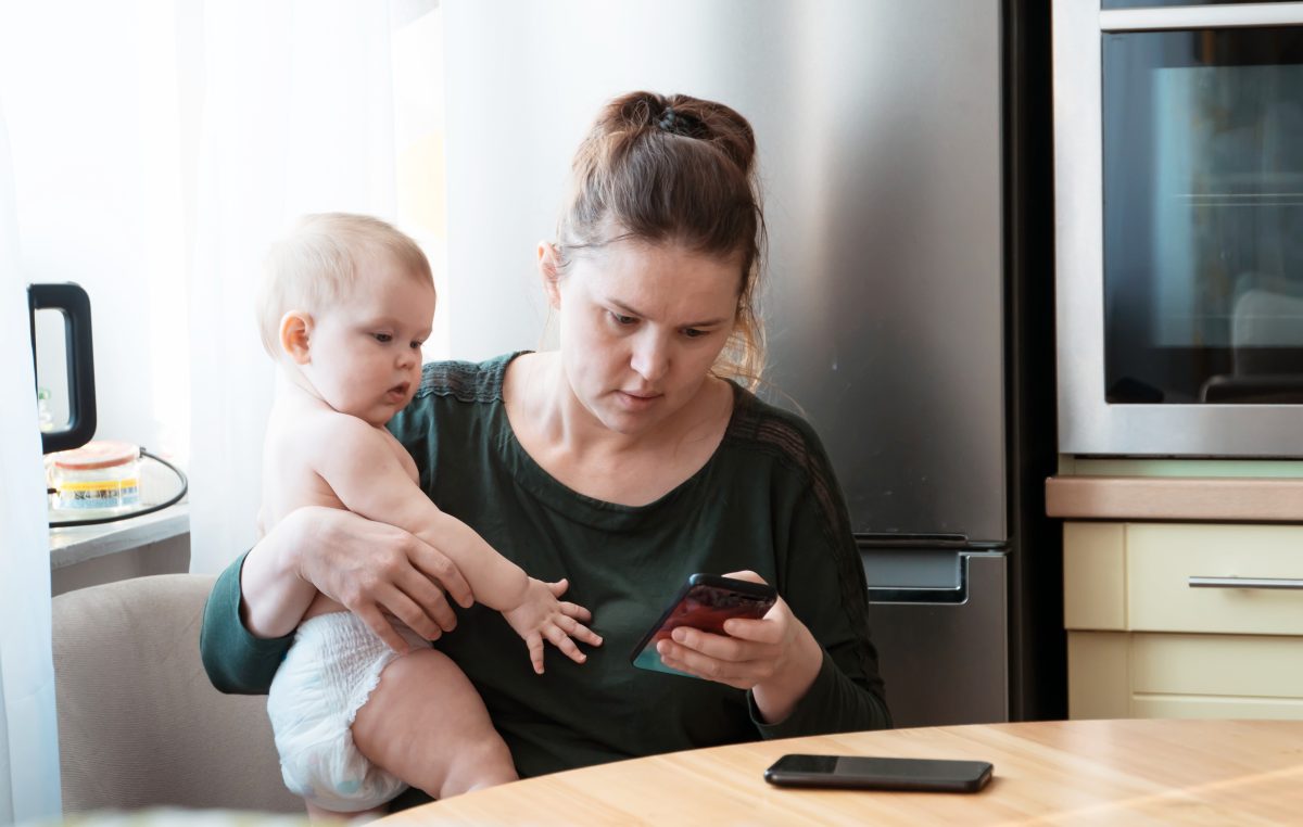 Mum on phone while holding baby.