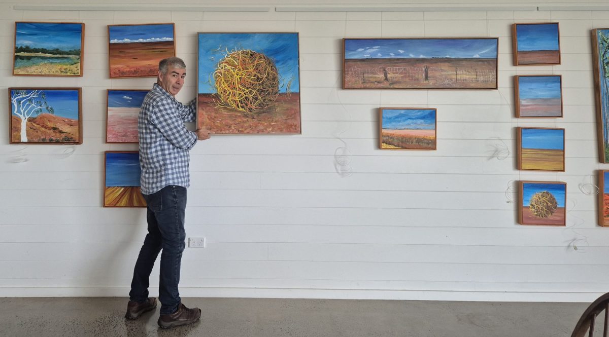 Person hangs a painting in a gallery