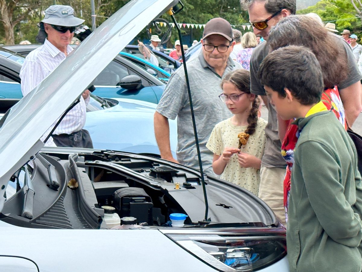 People look in the engine of an EV