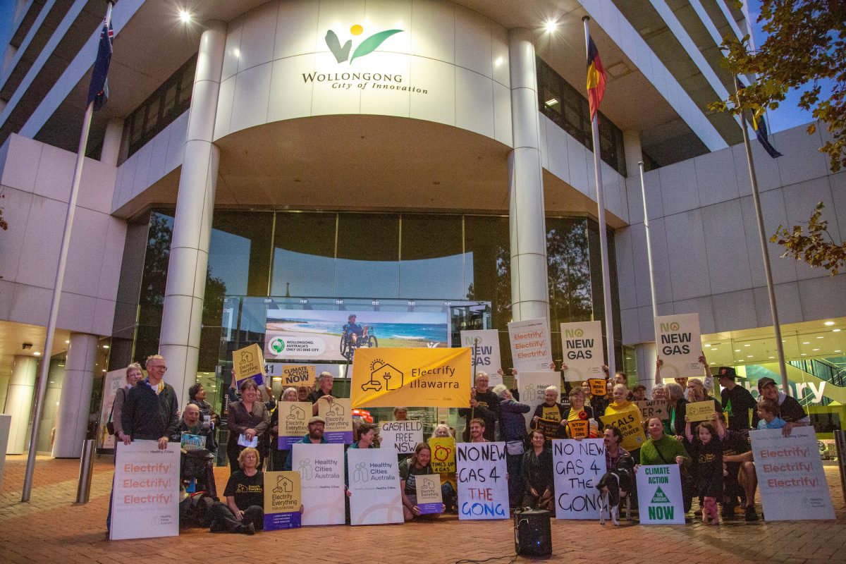 Rally members stand outside council with signs for no new gas