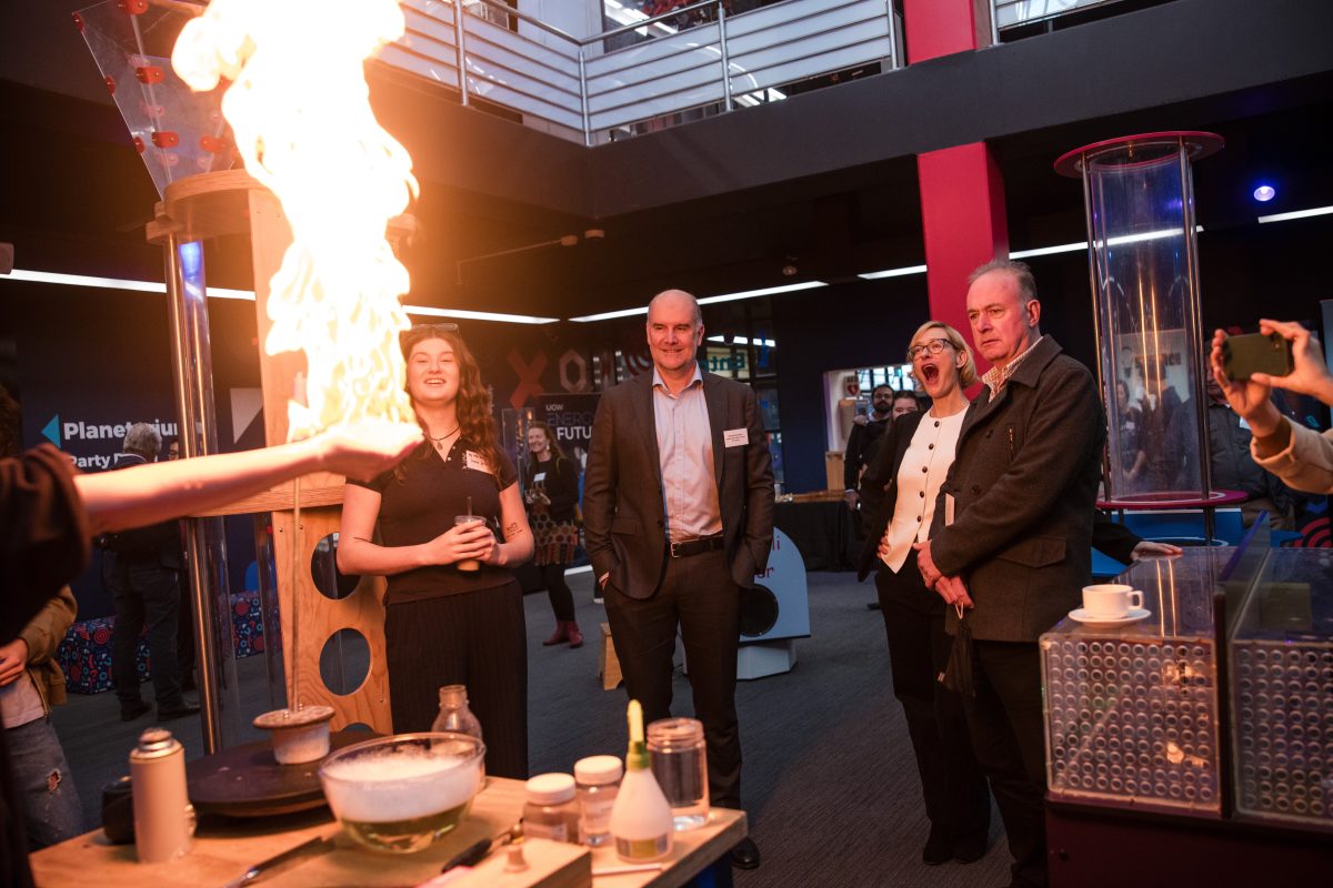 Person holds fire in their hand as a stunned audience watches