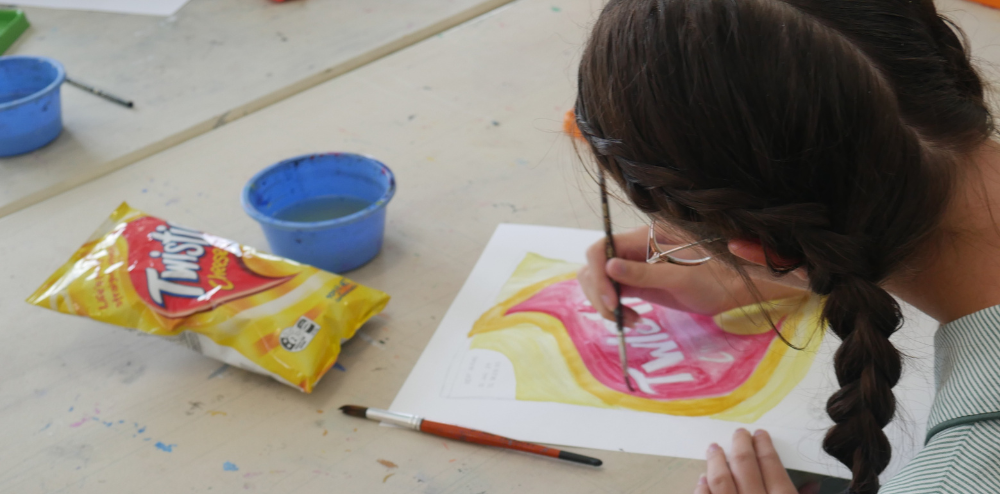 A person painting an artwork of a bag of twisties