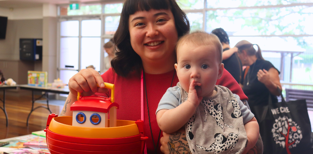 A person holding a baby and a toy boat