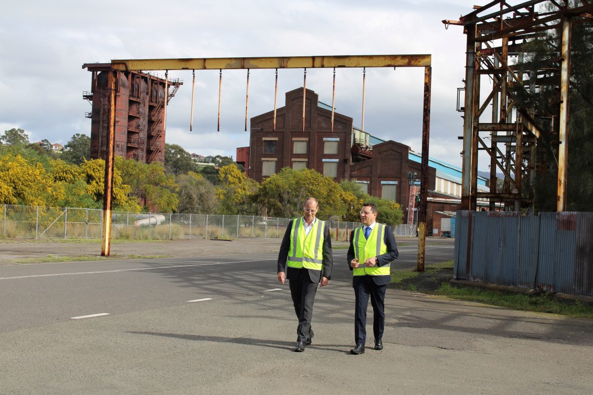 two men walking along in high-vis vests at an industrial site