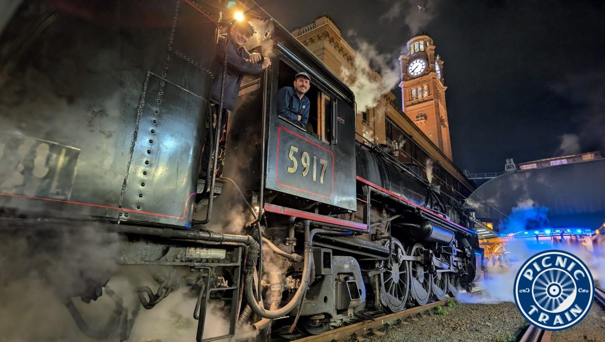 Conductors smile as they stand in an old steam train