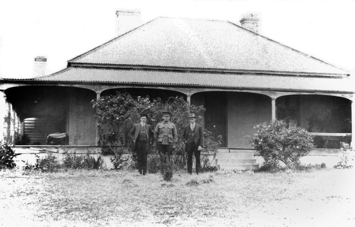 Black and white photo of house with soldier out front