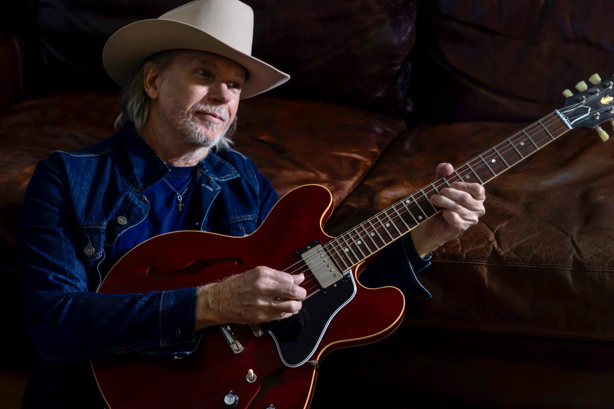 Rick Price strums a guitar