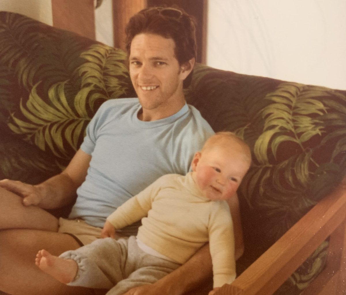 A man sitting on a couch with his baby