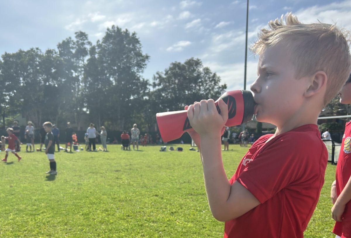 Young soccer player drinking water.