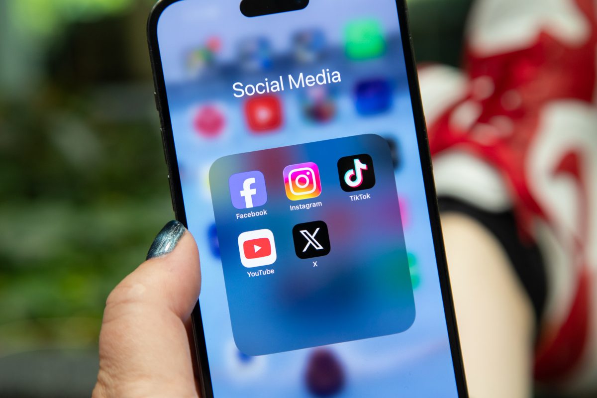 Hand holding phone with social media apps on screen