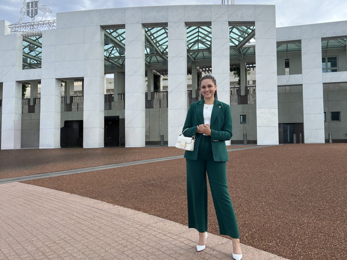 Young woman in an emerald green suit stands in front of the Australian embassy.