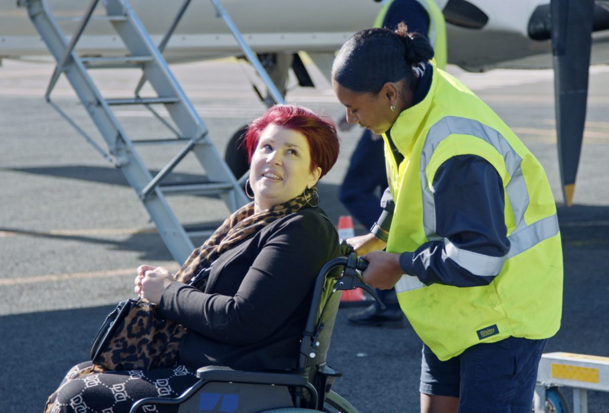 Airport worker pushing a woman in a wheelchair