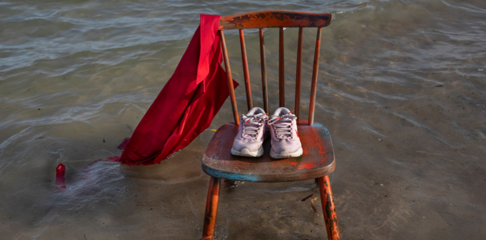 runners on a wooden chair sitting in water with a shirt hanging off the side