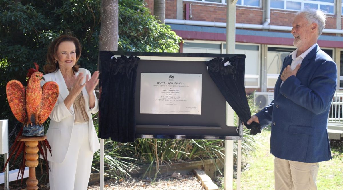 Two people unveiling a plaque