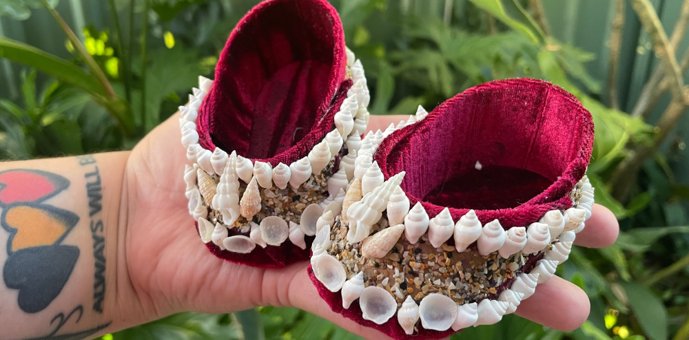 a hand holding pieces of shell art