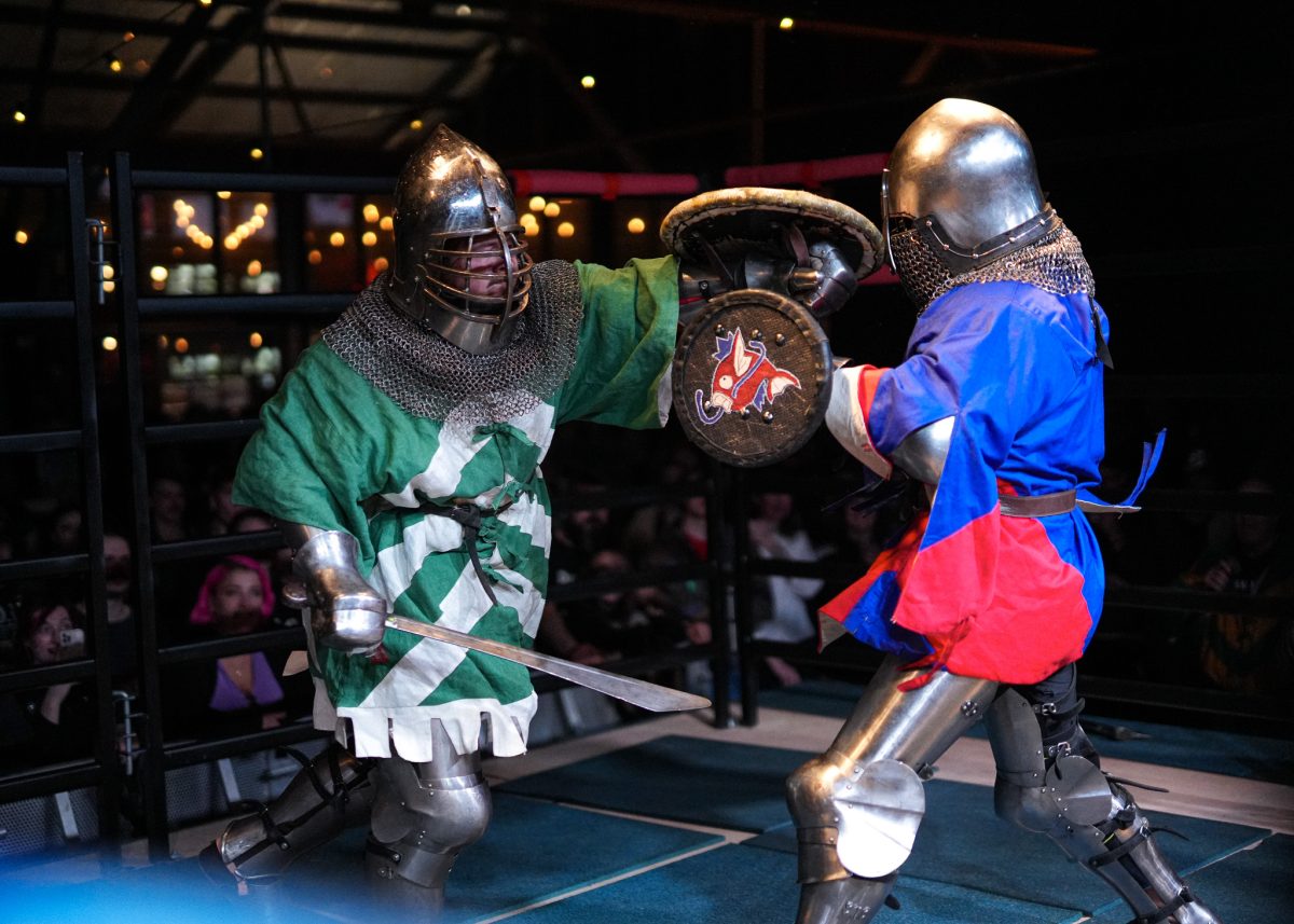 two armour-clad men in caged swordfight