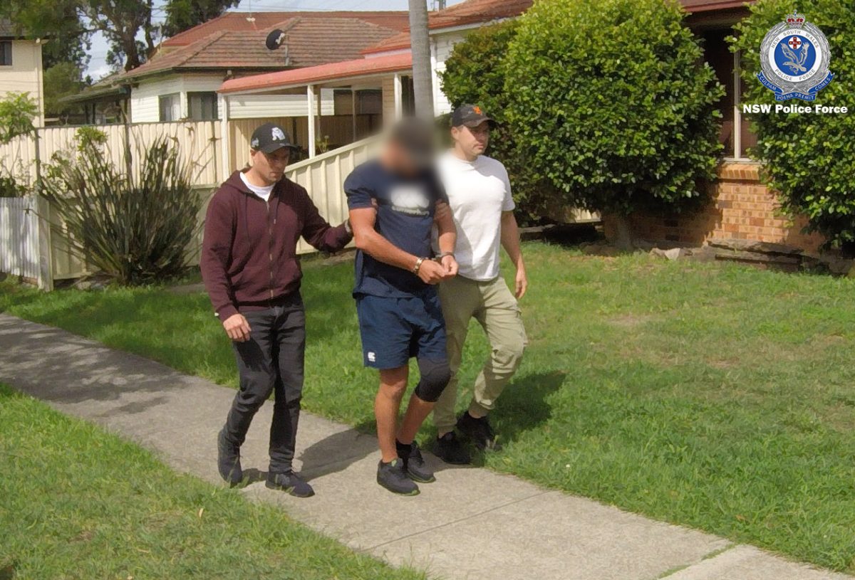 two detectives walking with arrested man.